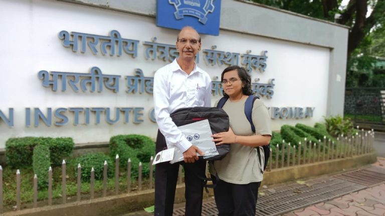 Ravina, IIT Mumbai student accepts laptop from volunteer Prakash Kadrekar, July 2024