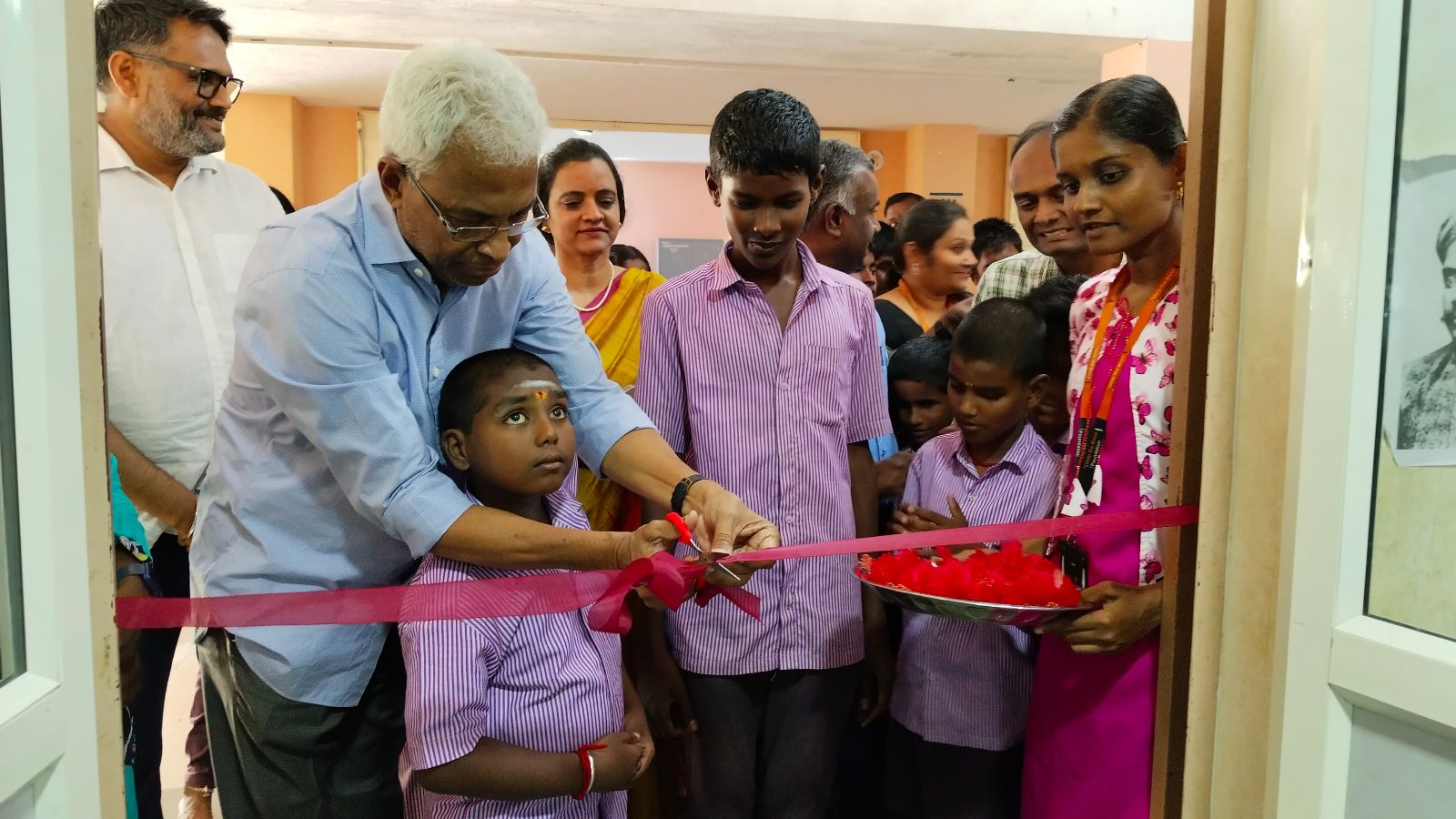 HTBF Trustee Mr. Nataraj Sankaran cuts the ribbon while visually impaired students and staff stand around him during the inaugural ceremony of the Resource Lab at the Government Higher Secondary School for the Visually Impaired in Thanjavur.