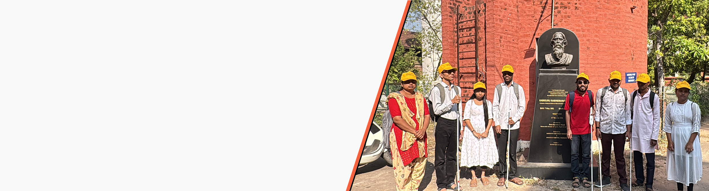 Visually impaired students holding white canes stand in front of the Rabindranath Tagore statue during a heritage walk visit.