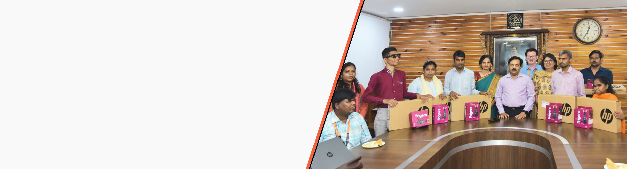 Dignitaries from Maharaja Sayajirao University and HTBF stand with visually impaired students holding laptops during the laptop distribution program.